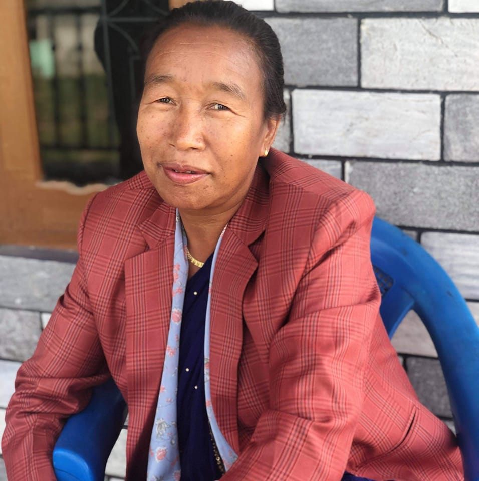 कुर्सीमा बसेर खैरो रंगको कोट लगाएर हल्का मुस्कान दिदैं छुपिमाया गुरुङ ।  