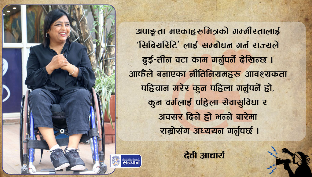 नेपाल स्पाइनल कर्ड इन्जरी खेलकुद संघ (एनएससिआइएसए) की अध्यक्ष देवी आचार्य अपाङ्गता भएका व्यक्तिहरूको अधिकार प्राप्तिको आन्दोलनमा सन् २००९ देखि क्रियाशील हुनुहुन्छ । याे ब्यानर फाेटाेमा उहाँ कालाे लुगा लगाएर ह्विल चेयरमा बसेर मुस्कुराइरहनु भएकाे तस्विर राखेर उहाँकाे काेटलाइ राखिएकाे छ । तस्विरकाे ब्याकग्राउण्ड हाते कागज राखिएकाे छ ।